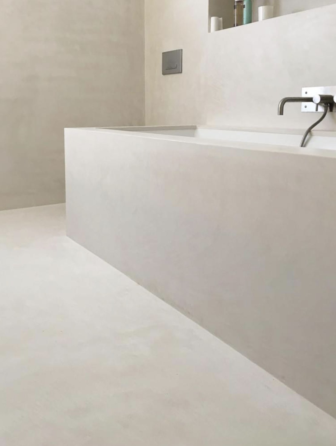 Built-in bathtub surround and floor finished in uniform warm beige microcement