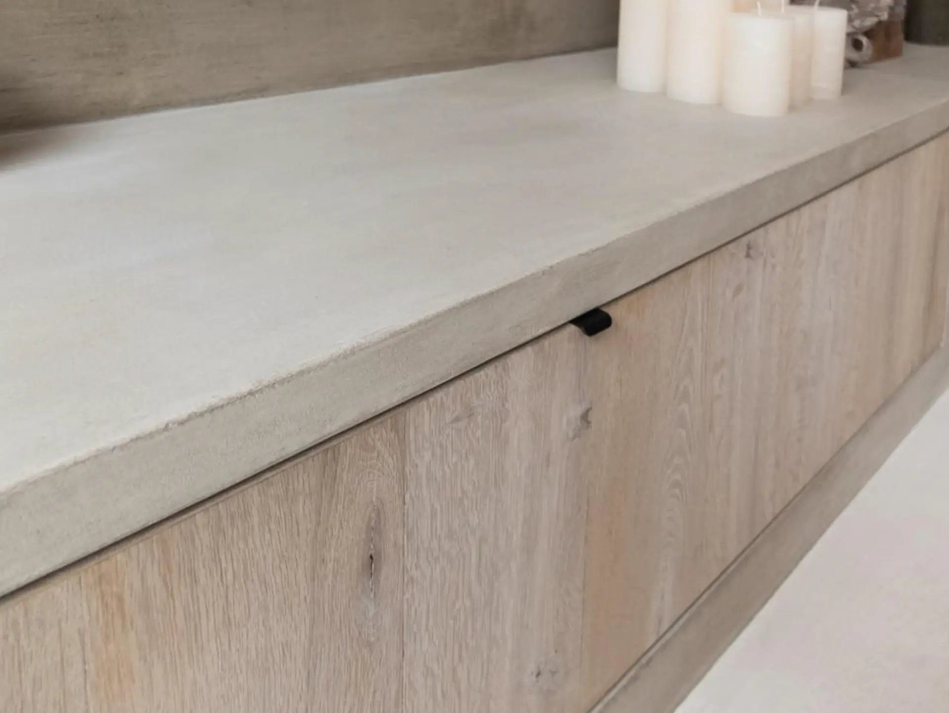 Poured mineral countertop above pale oak cabinetry in soft indirect light