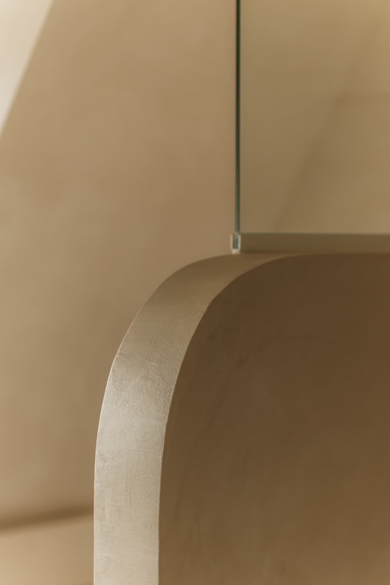 Curved plaster half-wall partition fitted with a glass screen in sandy beige