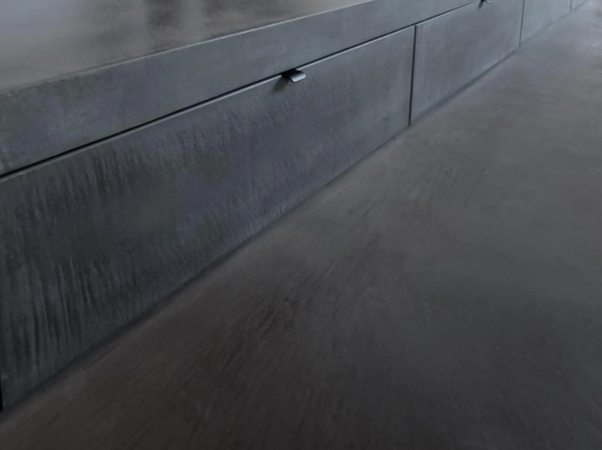 Dark charcoal mineral floor running into low built-in cabinetry