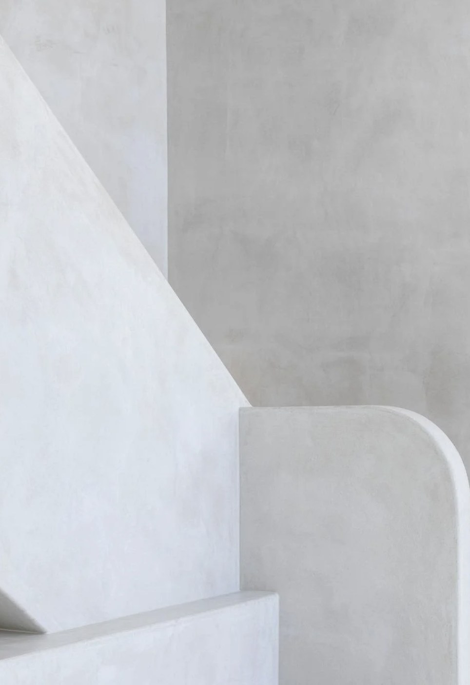 Sculptural microcement staircase balustrade in chalky off-white against a grey wall