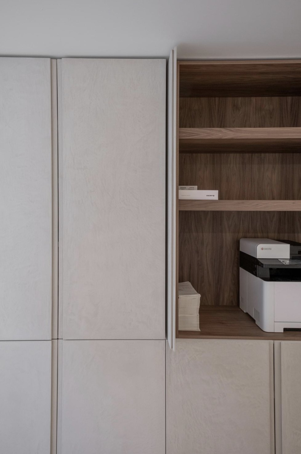 Pale plaster cabinet panels beside a warm wood veneer open shelf