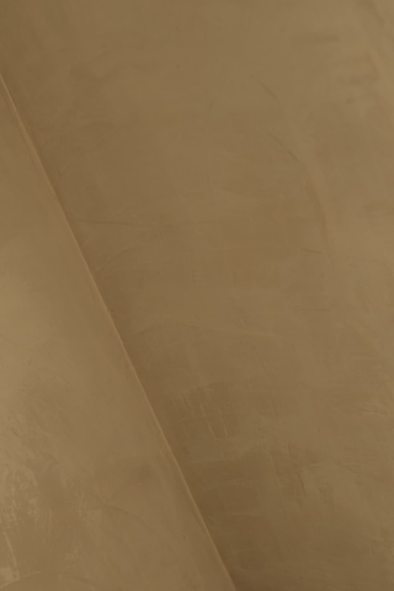 Internal corner of warm caramel plaster walls showing fine hand-applied texture