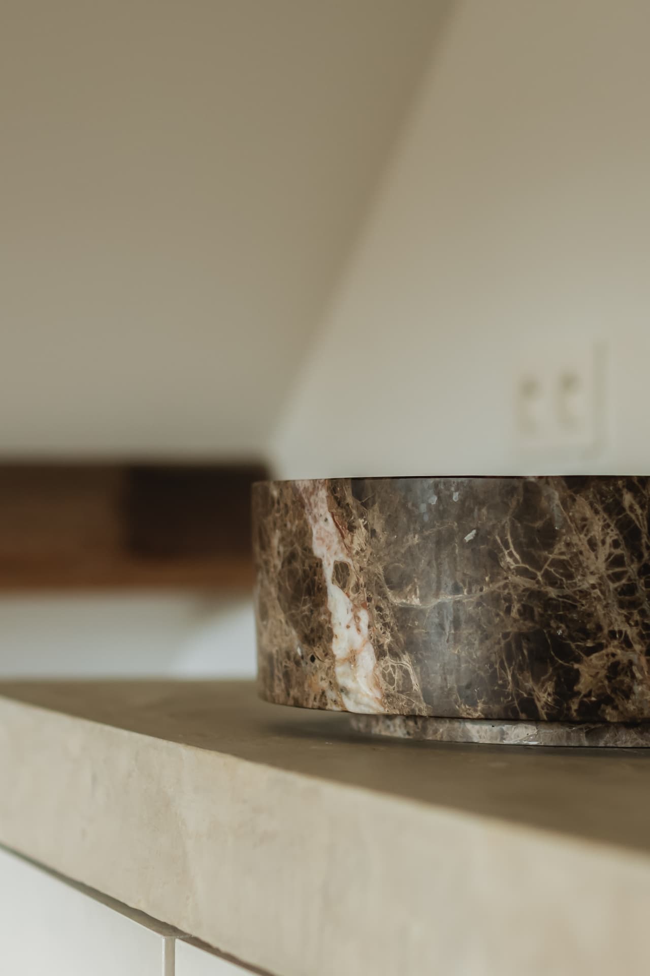 Dark veined marble vessel sink on a thick matte beige microcement countertop