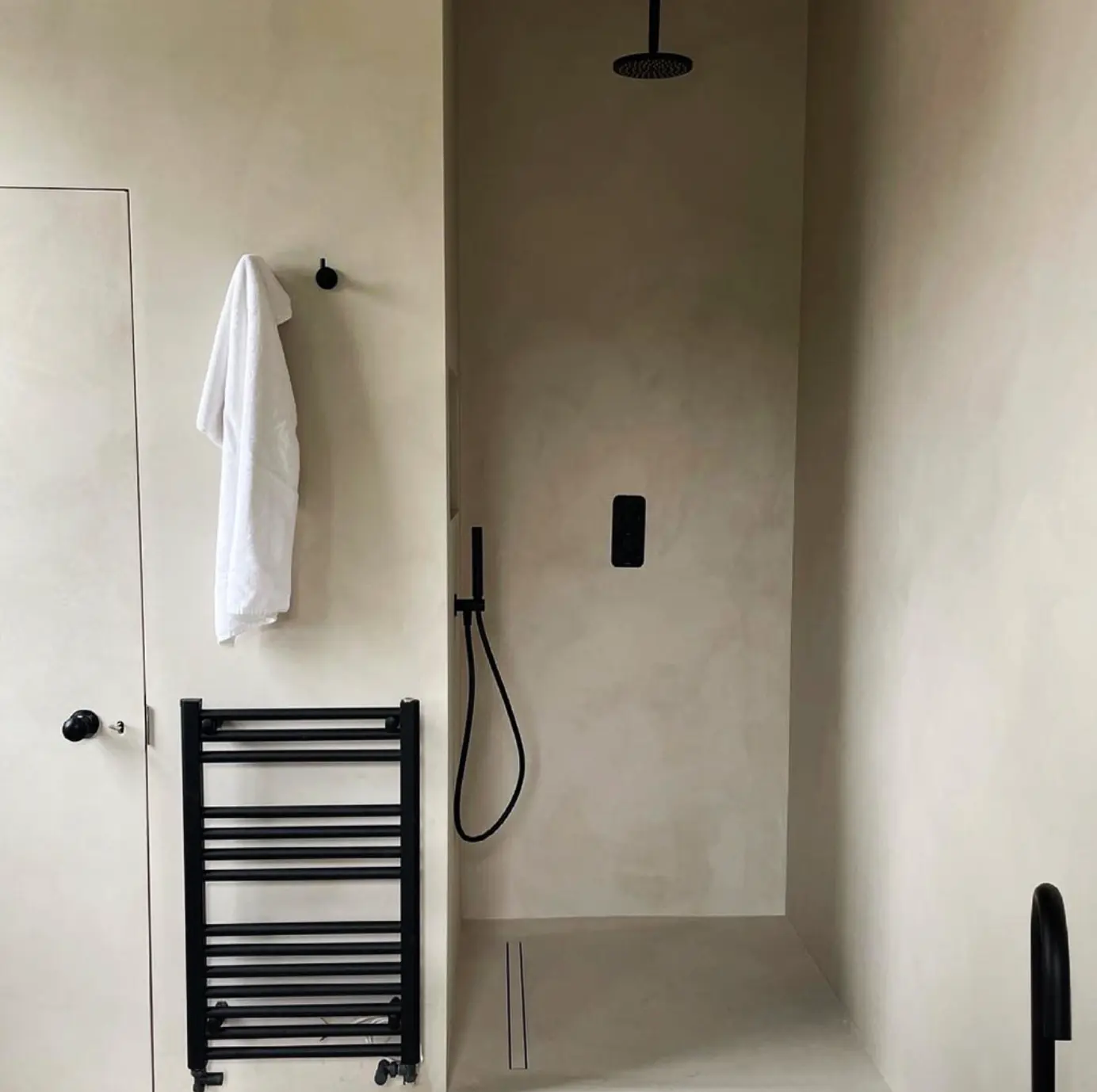 Walk-in shower with seamless microcement walls and floor in warm sandy beige